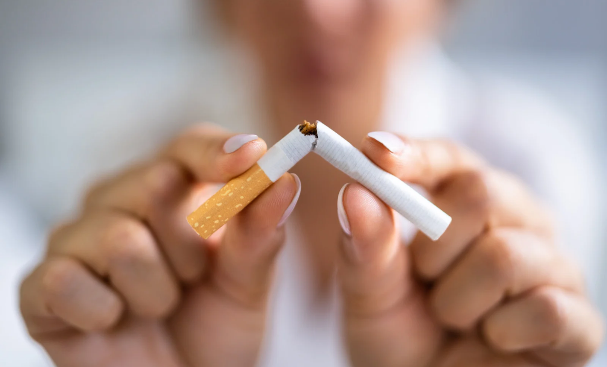 Femme coupant une cigarette pour symboliser sa décision d'arrêter de fumer, dans le cadre d'un accompagnement au sevrage tabagique par laser doux.