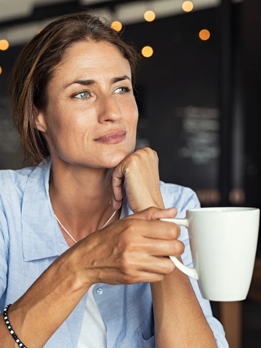 Femme tenant une tasse de café à la main, illustrant les habitudes du quotidien qui peuvent déclencher l'envie de fumer lors du sevrage tabagique.