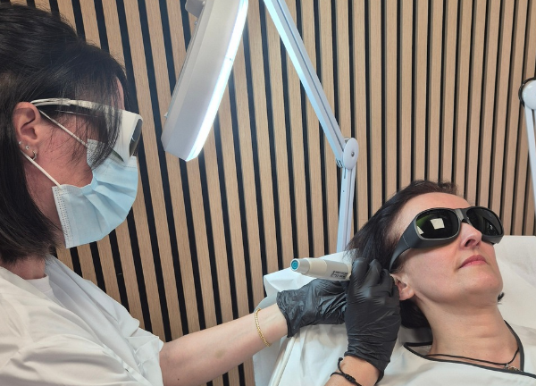 Praticienne réalisant une séance de réflexologie auriculaire au laser doux sur l'oreille d'une cliente, dans le cadre d'un accompagnement à l'arrêt du tabac.