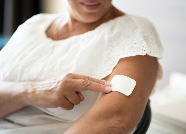 Application d'un patch à la nicotine sur le bras d'une personne pour accompagner le sevrage tabagique et réduire les symptômes du manque.