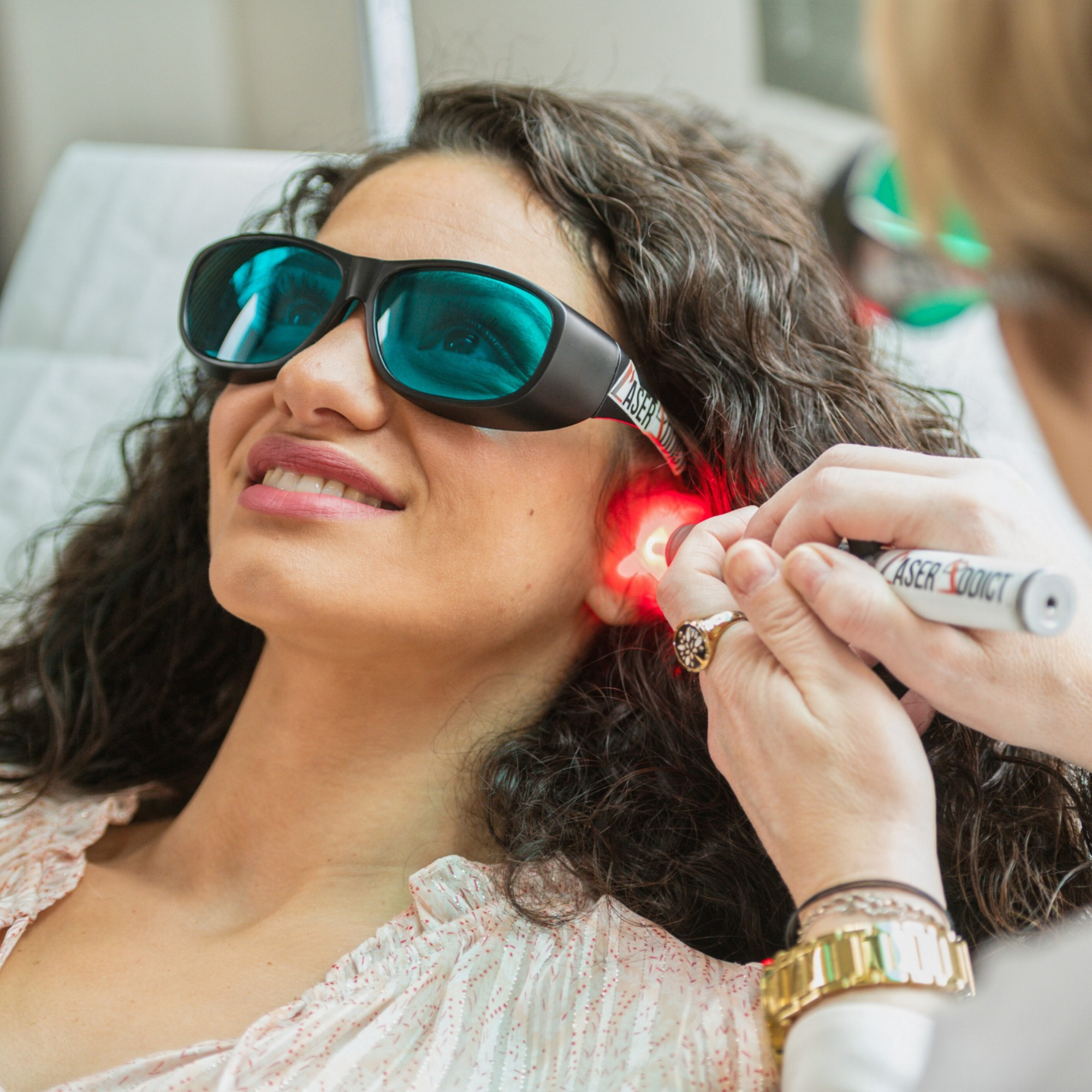 Femme souriante pendant une séance indolore d'auriculothérapie au laser doux, dans le cadre d'un accompagnement à l'arrêt du tabac.